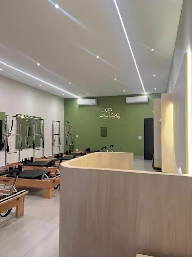 Sala do Pulse Pilates Fit com aparelhos Reformer Equipilates e parede verde com a logo